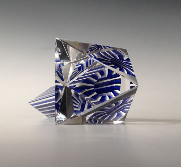 Material: Slipat och polerat prisma av murrini som limmats på en triangulär bipyramid polyeder gjord av slipat och polerat optiskt glas. Optiskt glas är glas av hög kvalitet med speciella ljusbrytande egenskaper för olika optiska instrument som till exempel teleskop. Mått: 7 x 7 x 7 cm Design, utförande, foto: Anna Carlgren